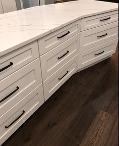 a white kitchen counter with black handles and drawers