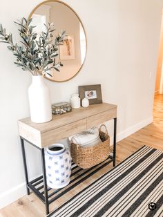 a white vase sitting on top of a wooden table next to a black and white rug