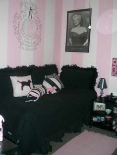 a living room with pink and white striped walls, black couches and pictures on the wall