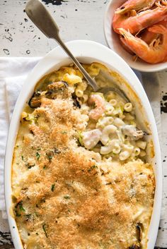 a casserole dish with shrimp and pasta in it next to a bowl of shrimp