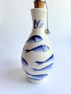 a blue and white vase with fish painted on the bottom is holding a corkscrew