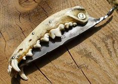 an animal's teeth are attached to a knife on a piece of wooden plank