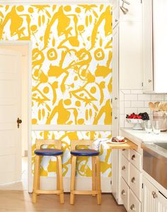 two stools sit in front of a yellow and white wall