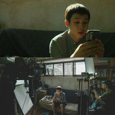 a boy sitting on a couch holding a cell phone in front of him and recording