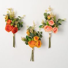 three bouquets of flowers are arranged on the wall