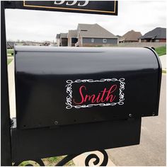 a black mailbox with the word smith on it sitting in front of a house