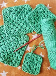 a green crocheted dishcloth and two knitting needles on a table with white stars