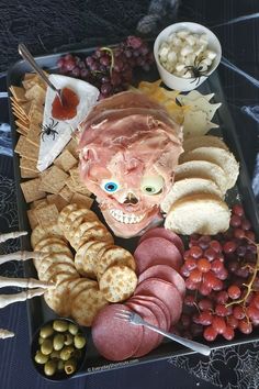 a platter with meat, cheeses, crackers and other foods on it