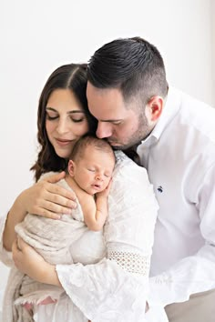 a man and woman holding a baby in their arms