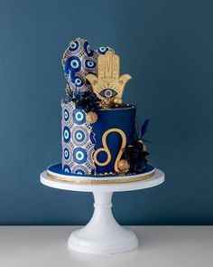 a blue and gold cake on a white pedestal