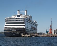 a large cruise ship docked in the water near some buildings and piers on a sunny day