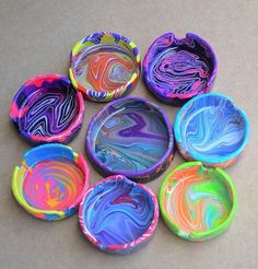 six colorful marbled paper plates sitting on top of a brown tablecloth covered floor