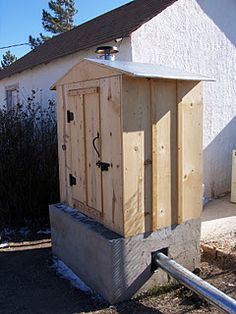 a wooden outhouse sitting in front of a white house