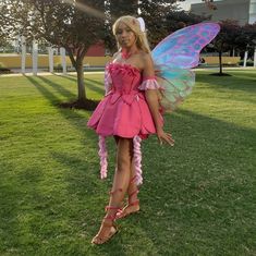 a woman dressed as a fairy standing in the grass