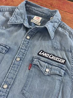 a denim shirt with the name landcruiser on it is sitting on a wooden surface