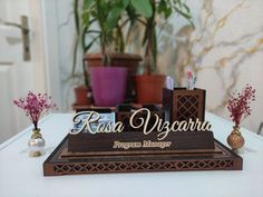 there is a desk set up with pens and pencils on it in front of a potted plant