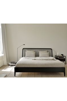 a bed with white linens and pillows in a minimalistic bedroom setting, along with a lamp