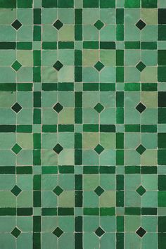 a green tiled wall with small squares on it