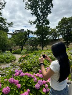 a woman taking a photo of flowers with her cell phone