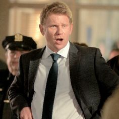 a man in a suit and tie walking through a crowd