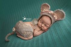 a newborn baby wearing a mouse hat and sleeping on a green blanket with her eyes closed