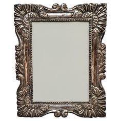 an ornate silver framed mirror on a white background