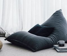 a bean bag chair sitting on the floor in front of a window with white curtains