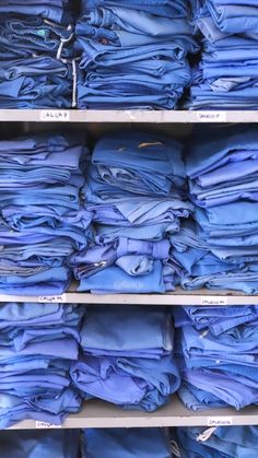 stacks of blue shirts are on shelves in a clothing store, with one folded up and the other unbuttoned