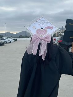 a person wearing a graduation cap and gown holding a book in their hand while standing in a parking lot