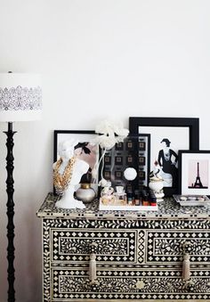 an ornate chest of drawers with pictures on it and a lamp in the corner next to it