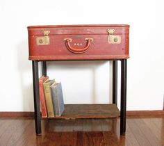 a red suitcase sitting on top of a wooden table next to two bookends