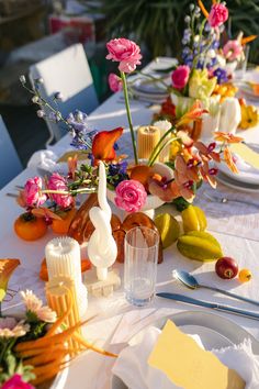 the table is set with flowers, fruit and other items for an elegant dinner party