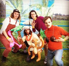 four people are posing for a photo in front of a fence with an animal costume on