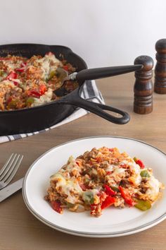 a white plate topped with food next to a skillet filled with casserole