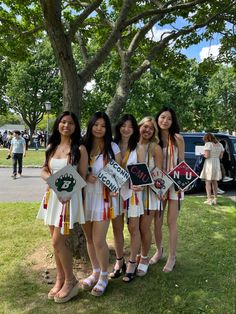 four girls are standing in front of a tree