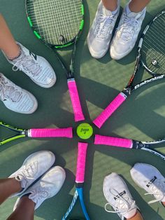 four tennis rackets arranged in a circle on the ground with people standing around them