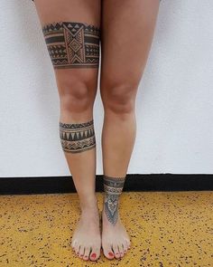 a woman's legs with tattoos on them standing in front of a white wall