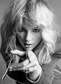 a black and white photo of a woman with long hair pointing her finger at the camera