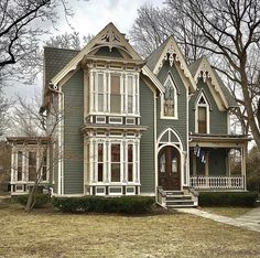 an old victorian style house with white trim on the front porch and two story windows