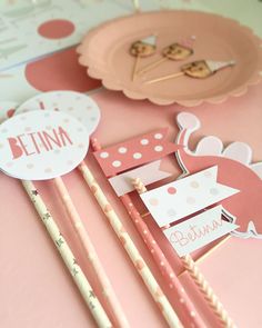 some pink and white paper items on a table with straws in the shape of birds