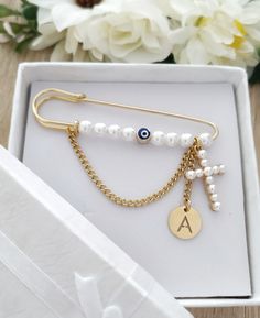 the initial charm bracelet is in a white box with gold chains and pearls on it