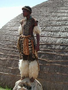 an african man standing in front of a thatched roof with his headdress