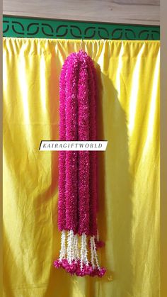 pink and white flowered scarf hanging from a yellow curtain with the word kartagiworld written on it