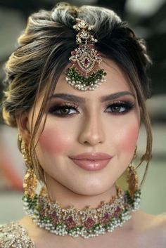 a woman in a bridal outfit with jewelry on her head and necklace around her neck