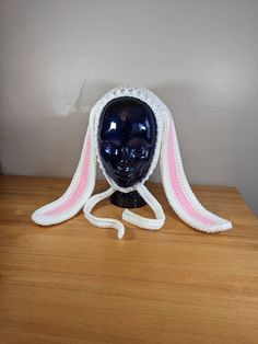 a crocheted hat with pink and white trim on top of a wooden table