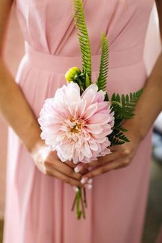 a bridesmaid holding a bouquet of flowers in her hands and wearing a pink dress