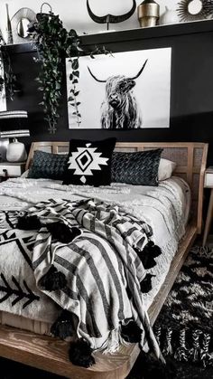 a bed with black and white decor on the wall next to a plant in a vase