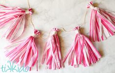 pink and white tassels hanging from string on marble counter top with text overlay that says diy tissue tassels