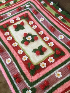 a crocheted blanket with strawberries and flowers on it