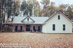 a white house in the woods with lots of leaves on the ground and trees around it